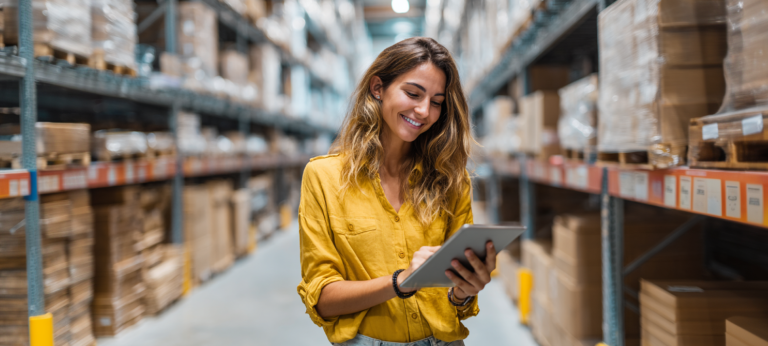 Eine Mitarbeiterin im Lager bearbeitet Pakete für den Versand, symbolisch für die Logistik im E-Commerce.