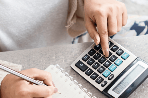 Person schreibt Notizen in ein Heft und benutzt dabei einen Taschenrechner, um Buchhaltungsaufgaben zu erledigen. Ideal zur Veranschaulichung von Eigenbelegen und Finanzverwaltung.